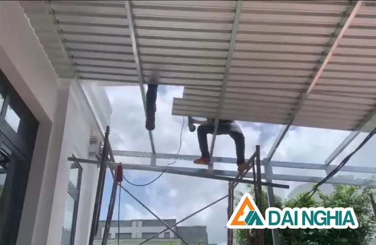 Hình ảnh thợ thi công đang lợp mái tôn cho khu vực sân