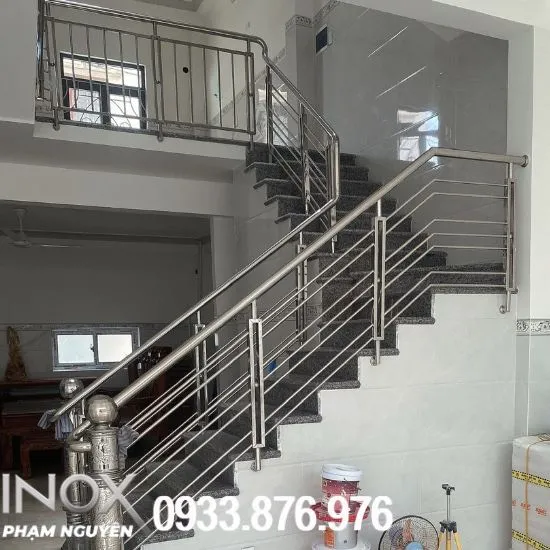 Cầu thang inox chữ L sáng bóng trên nền đá tối màu tạo hiệu ứng tương phản
