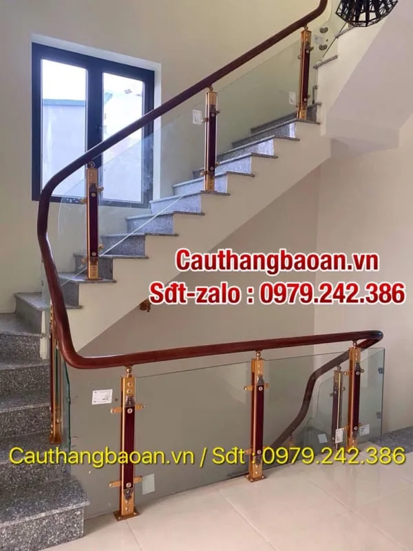 Cầu thang lan can kính cường lực tay vịn gỗ trong không gian ngập tràn cây xanh